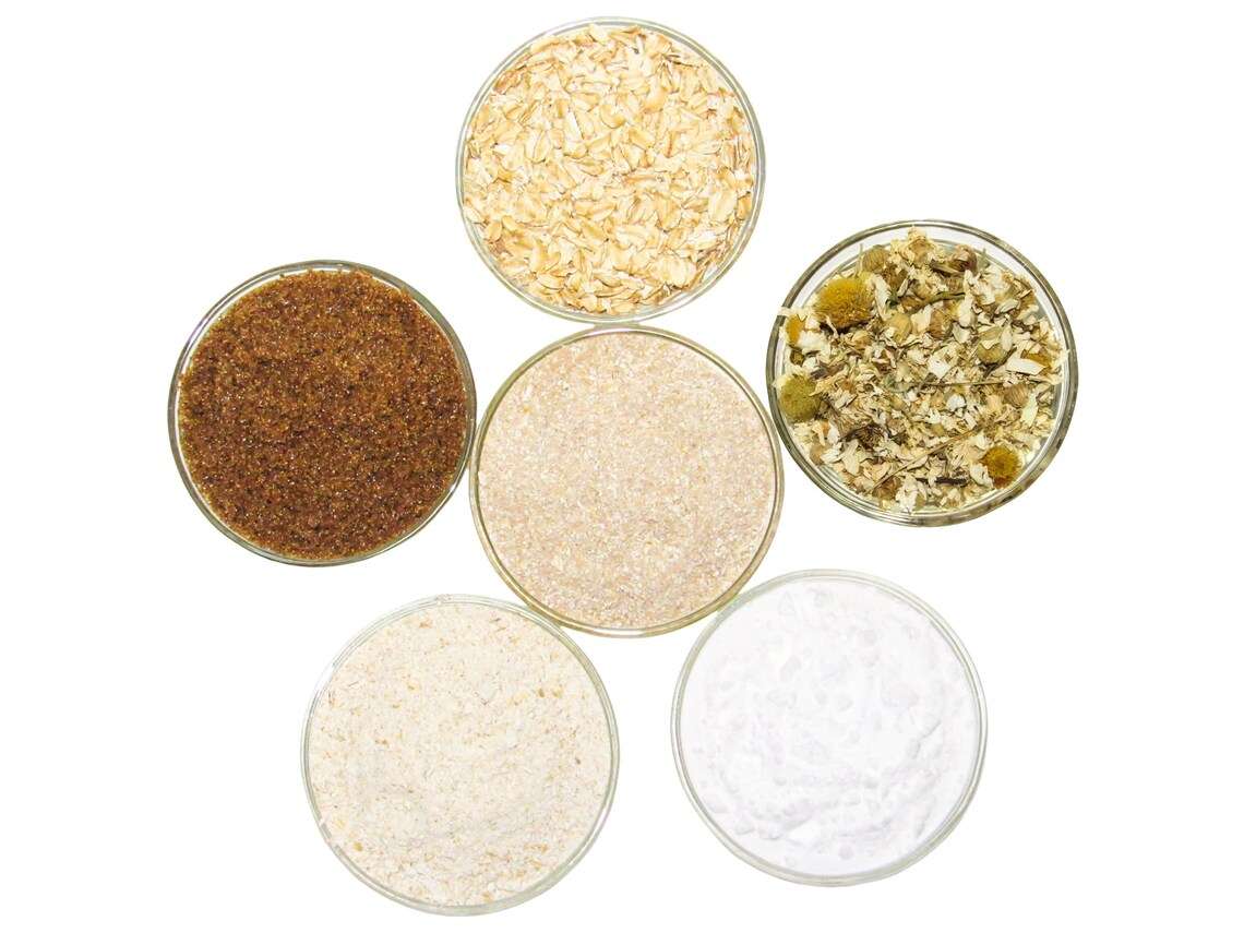 A selection of natural ingredients including whole oats, brown sugar, colloidal oatmeal, baking soda, and Chamomile for the Chamomile Oatmeal Bath Soak, displayed in separate bowls to highlight their purity and quality.