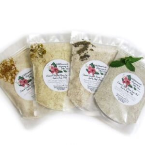 Four sealed packets of herbal bath soaks displayed side by side, each filled with a different type of organic bath soak - calendula with yellow petals on the left, chamomile with chamomile petals in the second position, lavender with purple lavender buds in the third position, and mint with green mint leaves on the right.