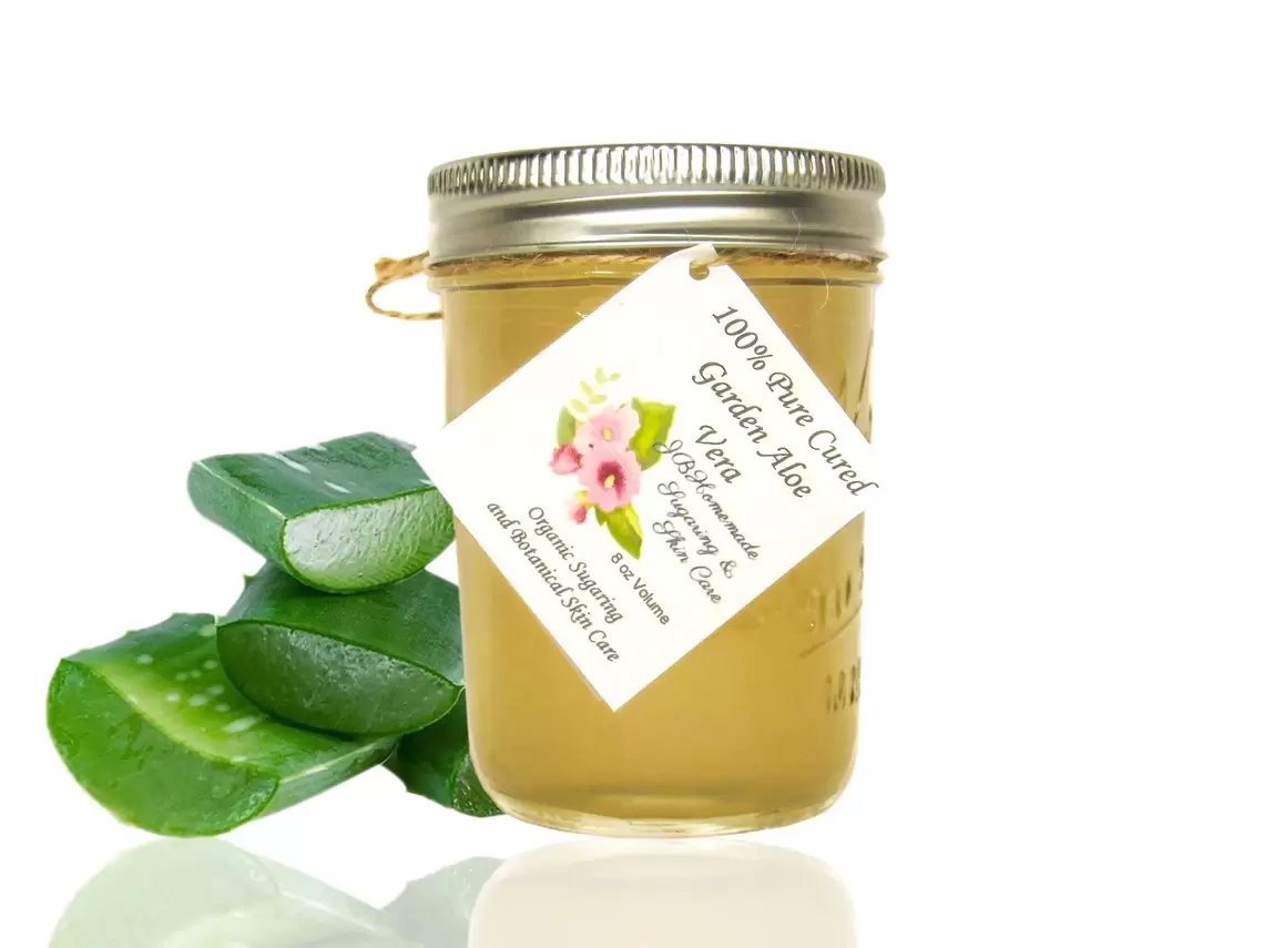 Front view of a mason jar overflowing with pure aloe vera gel, flanked by layers of fresh aloe vera slices, highlighting natural skincare.