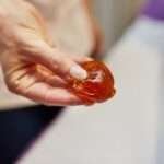 An aesthetician uses her fingers to hold up a ball sugaring paste for hair removal, demonstrating the proper size ball to use while preparing it for a treatment that leaves the skin smooth and hair-free.