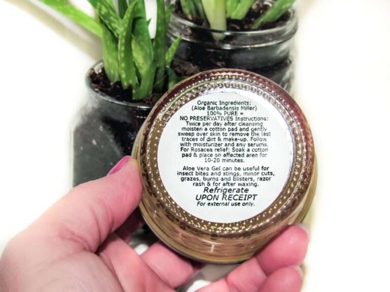 Organic Aloe Vera Gel Product: Hand holding a container with detailed usage instructions, near potted plants.