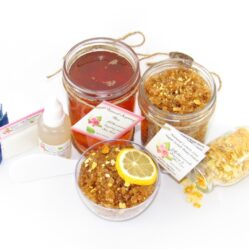 A bundle featuring an 8 oz mason jar of softer consistency sugaring wax, paired with a jar of Lemon Zest Cane Sugar Body Scrub. and Colloidal Oatmeal Brown Sugar Dry Body Scrub, a small bottle of pure aloe vera, a pouch of cornstarch, denim strips, an applicator, with a spilled jar of dried lemon zest and a bowl of the body scrub adorned with a lemon slice.