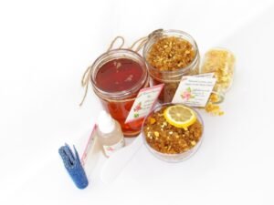 A bundle featuring an 8 oz mason jar of softer consistency sugaring wax, paired with a jar of Lemon Zest Cane Sugar Body Scrub. and Colloidal Oatmeal Brown Sugar Dry Body Scrub, a small bottle of pure aloe vera, a pouch of cornstarch, denim strips, an applicator, with a spilled jar of dried lemon zest and a bowl of the body scrub adorned with a lemon slice.
