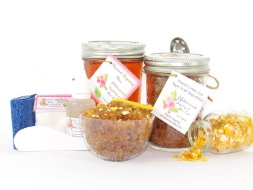 A bundle featuring an 8 oz mason jar of softer consistency sugaring wax, paired with a jar of Lemon Zest Cane Sugar Body Scrub. and Colloidal Oatmeal Brown Sugar Dry Body Scrub, a small bottle of pure aloe vera, a pouch of cornstarch, denim strips, an applicator, with a spilled jar of dried lemon zest and a bowl of the body scrub adorned with a lemon slice.