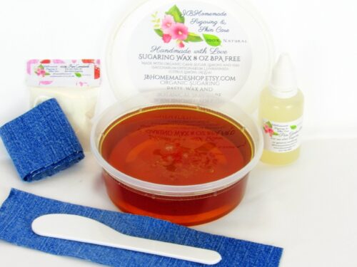 An 8-ounce tub of JBHomemade Sugaring Wax is presented with its included pouch of cornstarch, bottle of aloe vera, denim strips and applicator.