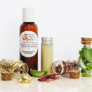 A front view of an all-natural facial cleanser in an amber bottle surrounded by small, corked glass bottles containing sprinkles of Red Rose, Aloe Vera and Chamomile ingredients. A clear glass bottle showcases the face wash's color and texture.