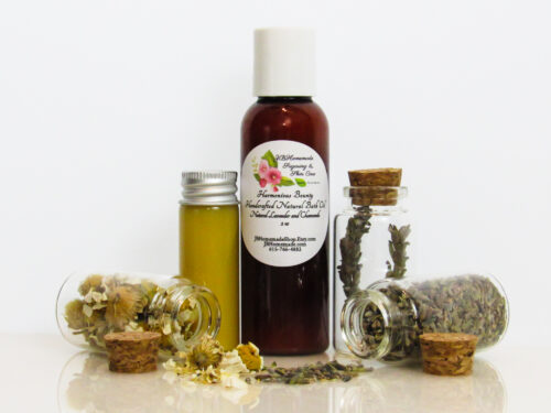 A front view of an all-natural bath oil in an amber bottle surrounded by small, corked glass bottles containing Lavender and Chamomile ingredients and sprinkles of the same. A clear glass bottle showcases the bath oil's color and texture.