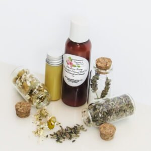 An angled, front view of an all-natural bath oil in an amber bottle surrounded by small, corked glass bottles containing Lavender and Chamomile ingredients and sprinkles of the same. A clear glass bottle showcases the bath oil's color and texture.