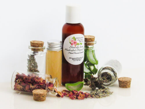 Naturally Serene Lavender and Red Rose Toner in an amber bottle, surrounded by organic ingredients like aloe vera slices, dried lavender sprigs, witch hazel, and red rose petals on a white surface.