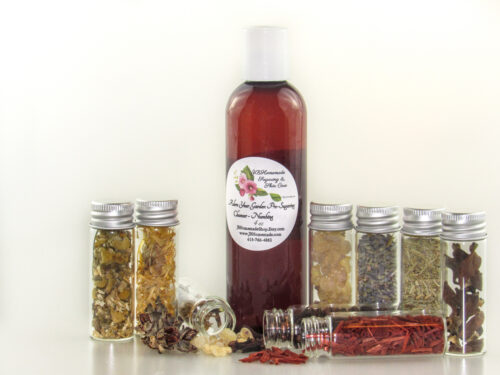 A bottle of Adorn Your Garden Sugaring Cleanser and Prep surrounded by small jars containing its all-natural ingredients like Chamomile, Calendula, Frankincense, Clove, Sandalwood, Lavender, Rosemary, and Ylang Ylang Extra. Side right view.