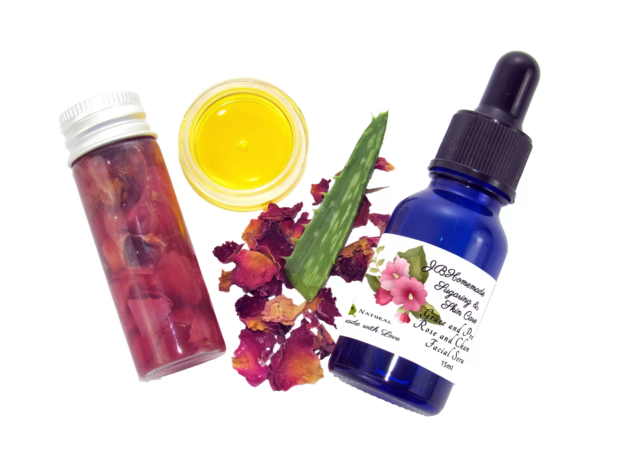 Top view featuring the cobalt serum bottle, infused oils, adorned with an arrangement of dried roses and a fresh aloe leaf.