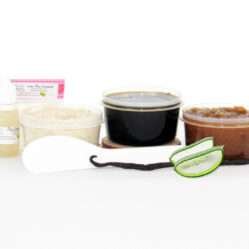 The home sugaring hair removal starter kit comes with a 2 oz tub of firm sugaring paste, a tub of Vanilla Aloe Brown Sugar Body Scrub, a tub of Colloidal Oatmeal Brown Sugar Dry Body Scrub, a small bottle of pure aloe vera, a pouch of cornstarch, an applicator, along with a vanilla bean and a slice of aloe plant for illustration.