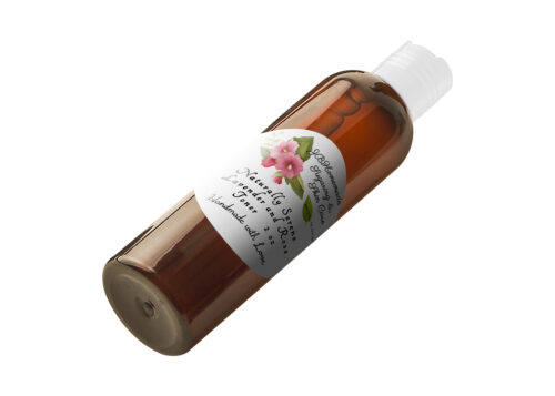 A view from an angle of JBHomemade Sugaring and Skin Care's handcrafted Naturally Serene Lavender and Rose Toner in an amber 2 oz bottle, displaying the front label.