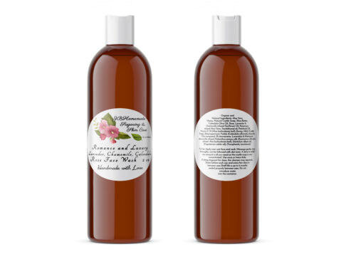 A pair of JBHomemade Sugaring and Skin Care's handcrafted Romance and Luxury Calendula, Rose, Lavender, Chamomile, Rosemary, Aloe Vera, Sandalwood and Patchouli Oil Face Wash in amber 2 oz bottles on a white background. The bottle on the left displays the front label, while the bottle on the right shows the back label. The back label lists the pure ingredients, usage and care instructions, and shelf life of the product.